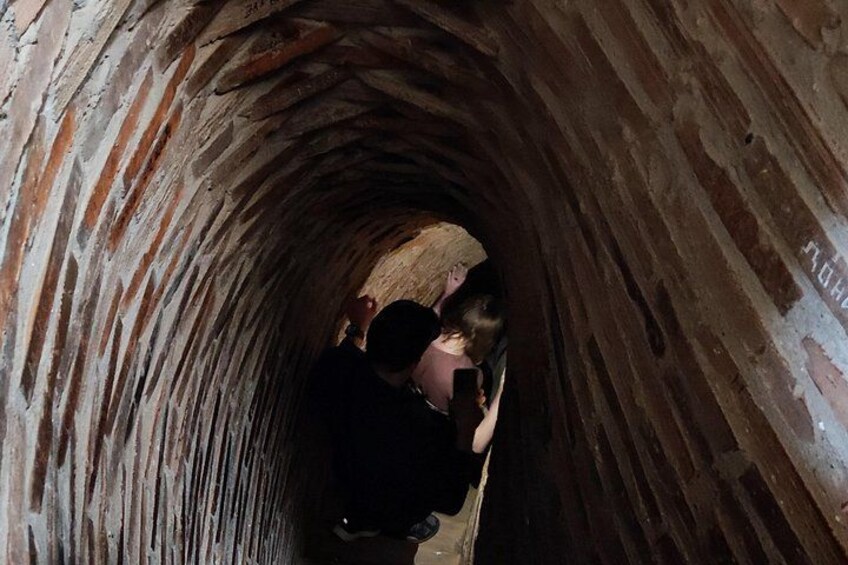 A narrow stone tunnel with a person standing in the center. 2
