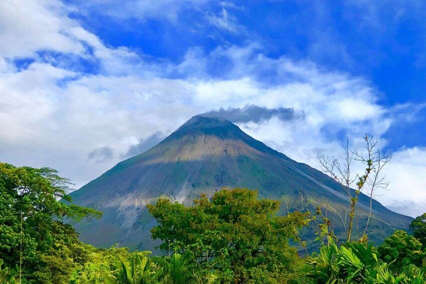 A mountain with a forested foreground and a partly cloudy sky. 5