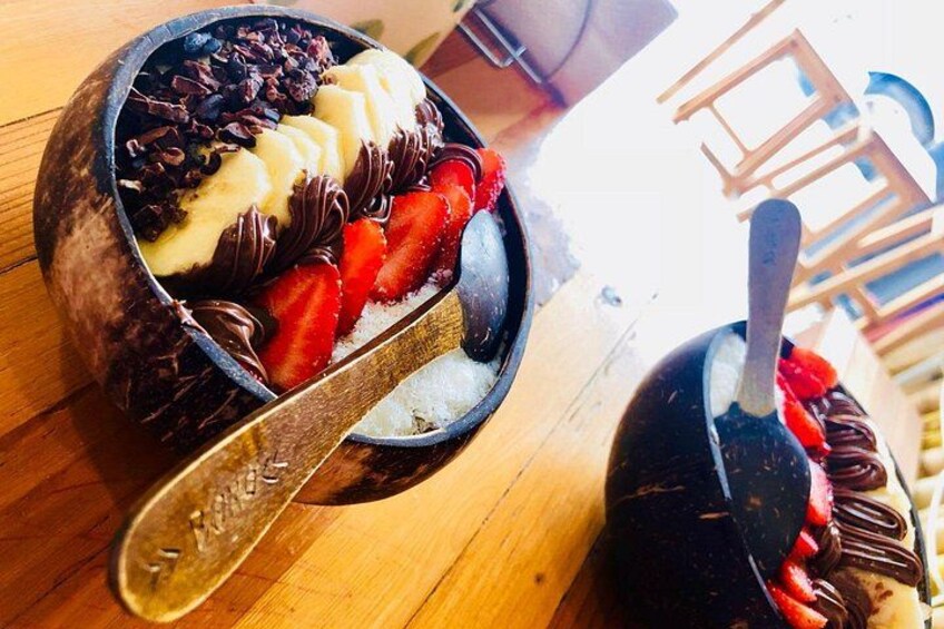 A dessert bowl with chocolate, strawberries, and bananas on a wooden table. 2