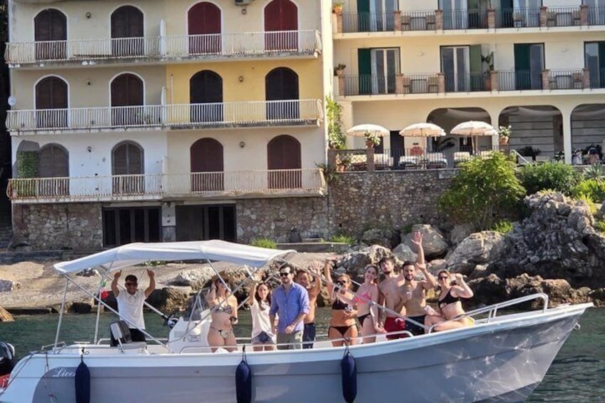 A boat with people on it, a stone wall, and buildings with balconies in the background. 2