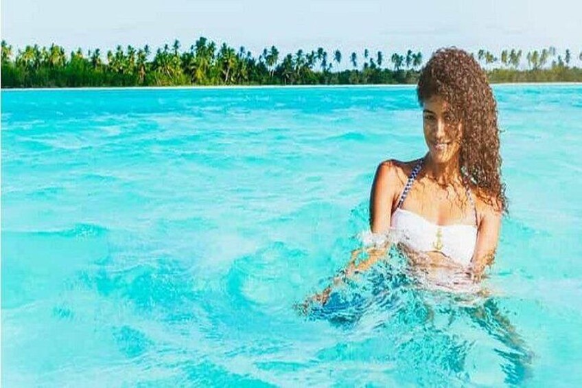 A person in a swimming pool with clear blue water and a tropical background. 5