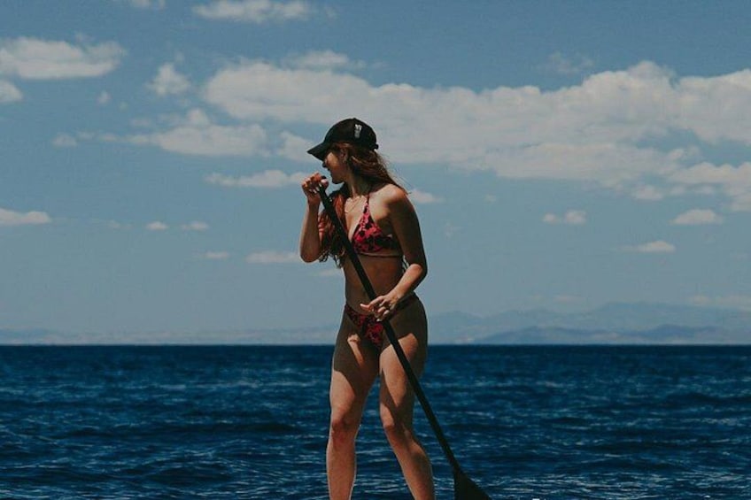 A person standing in the ocean with a paddleboard. 4