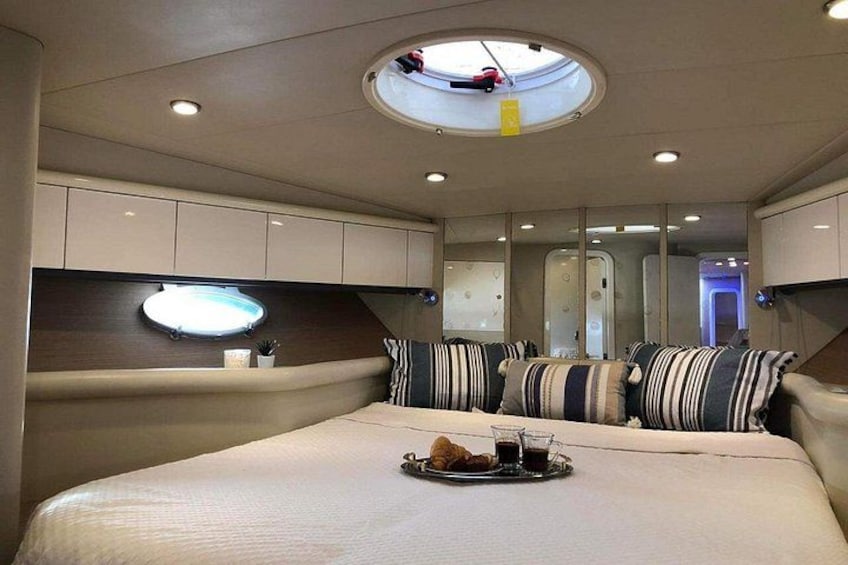 A well-lit, modern interior with a large bed, striped pillows, and a breakfast tray. 2