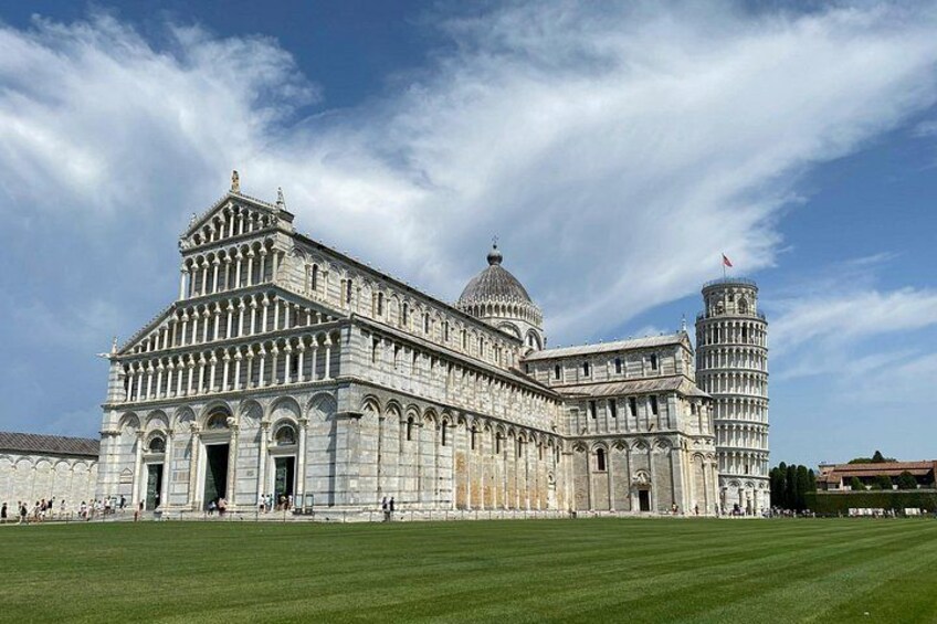 The Leaning Tower of Pisa with a grassy foreground and a clear sky. 2