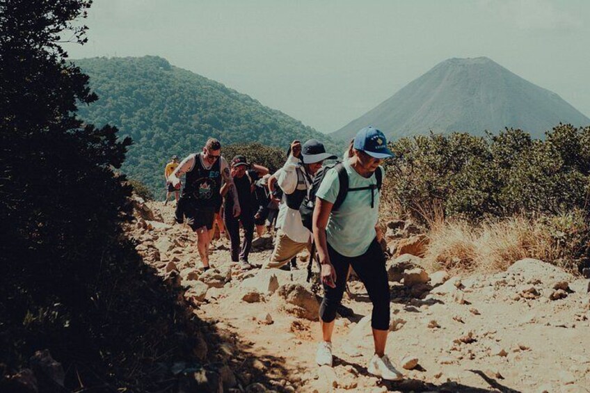 Un grupo de excursionistas en un sendero pedregoso con una montaña al fondo. 2