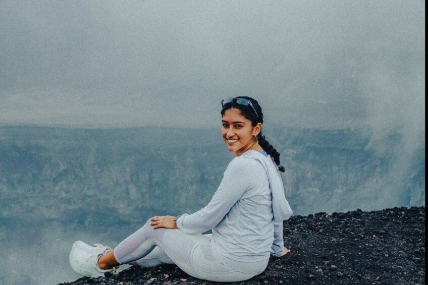 A person sitting on a rocky surface with a mountainous landscape in the background. 3