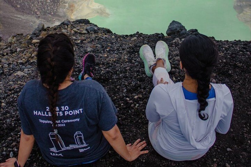 Dos personas sentadas en una costa rocosa con una masa de agua al fondo. 3