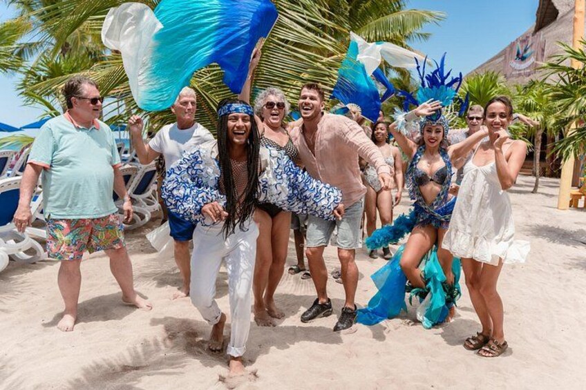A group of people dancing on a sandy beach with palm trees in the background. 4