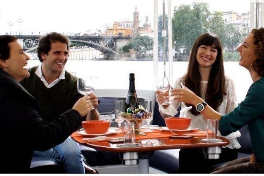 Un grupo de personas sentadas en una mesa con una botella de champán, copas y un bol. 1