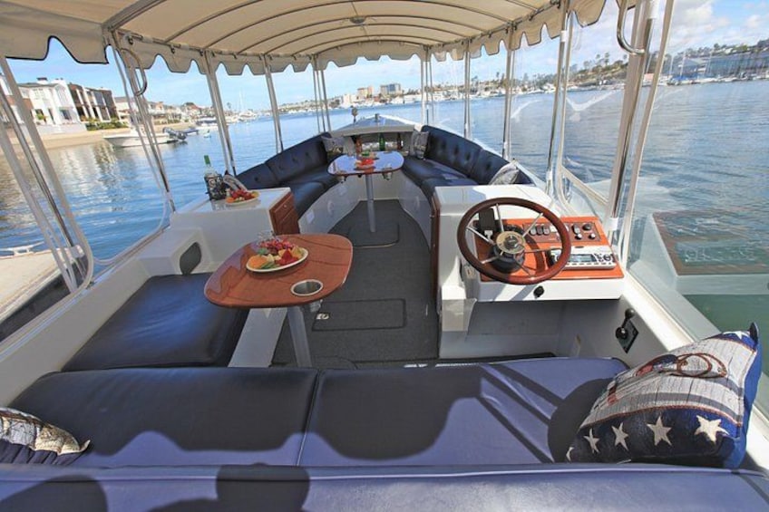 Interior de un barco con timón, asientos y una mesa con comida. 2