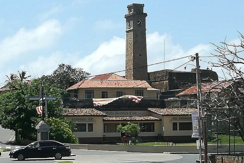 A building with a clock tower, a sign for 'Dalle Services Club,' and a parked car. 5
