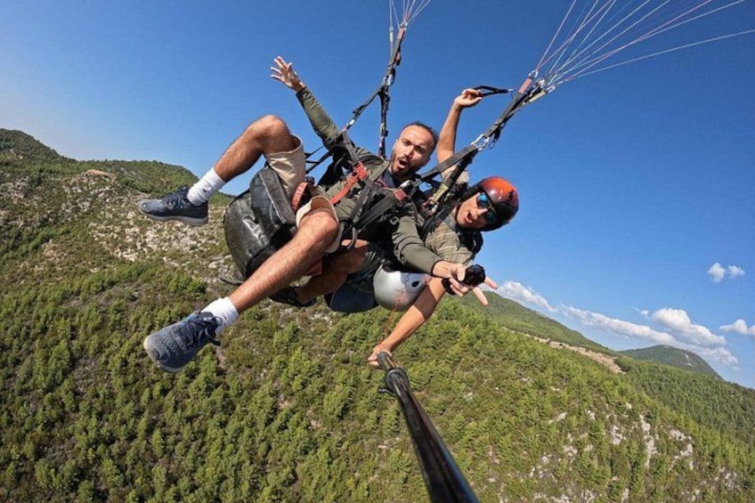 Zwei Personen mit Gleitschirm über einer gebirgigen Landschaft. 4