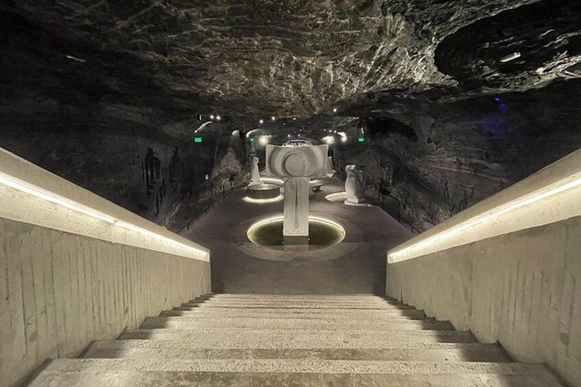 A staircase leading to a circular platform with a central structure, surrounded by walls and lighting. 5