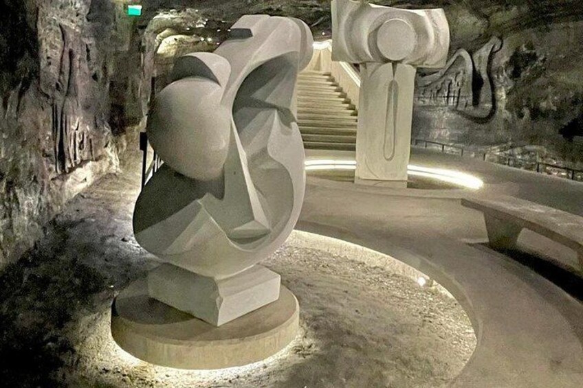 A modern sculpture in a dimly lit, rocky cave environment. 4