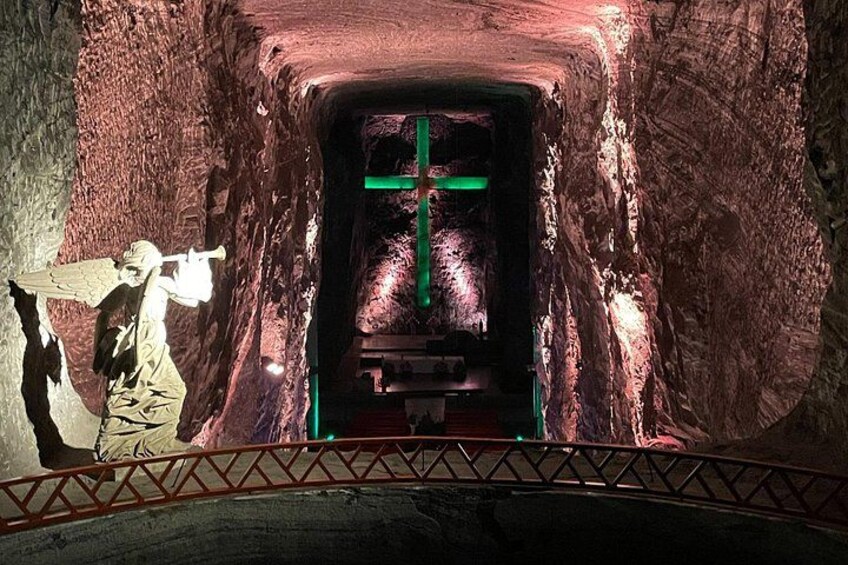 A tunnel with a statue of an angel and a green cross. 3