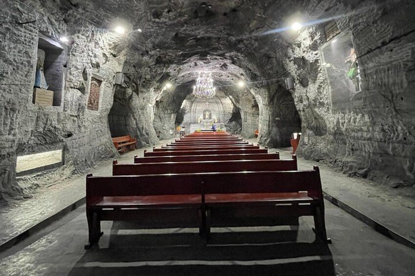 A long, dimly lit tunnel with benches aligned along the walls. 2