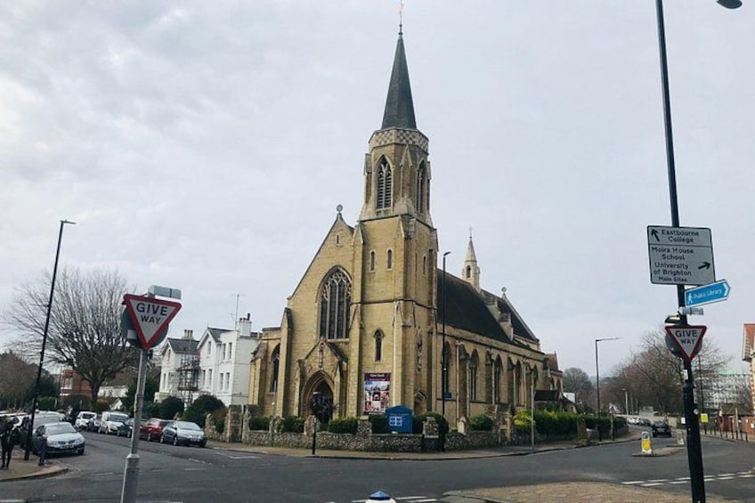 A church with a tall steeple, a 'Give Way' sign, and directional signs for nearby locations. 3