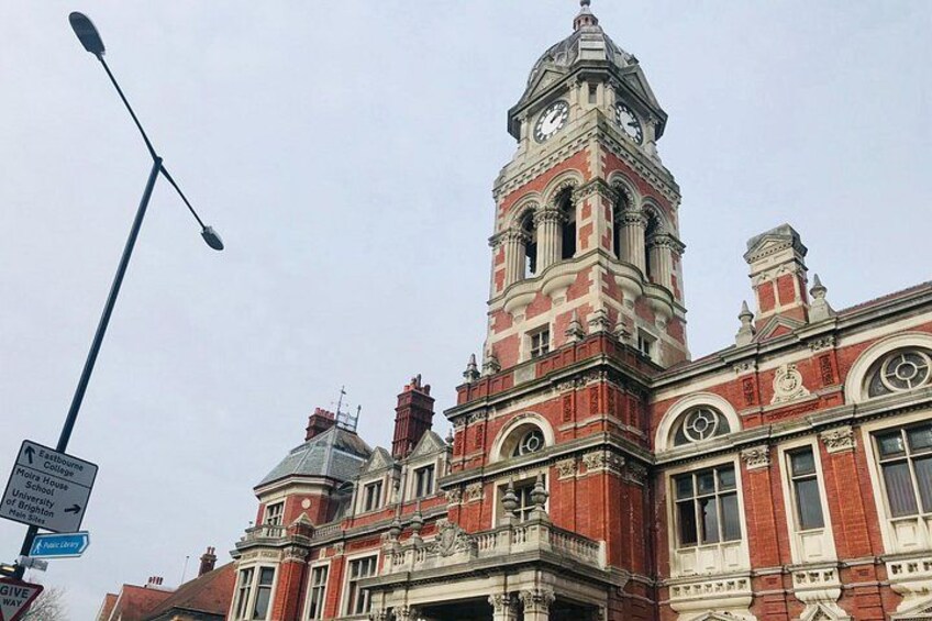 A historic building with a clock tower, ornate architecture, and a street sign. 2