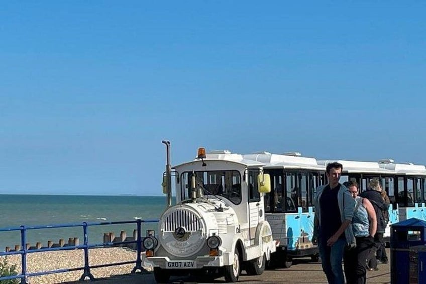 A vintage tram on a seaside boardwalk with a clear sky. 5