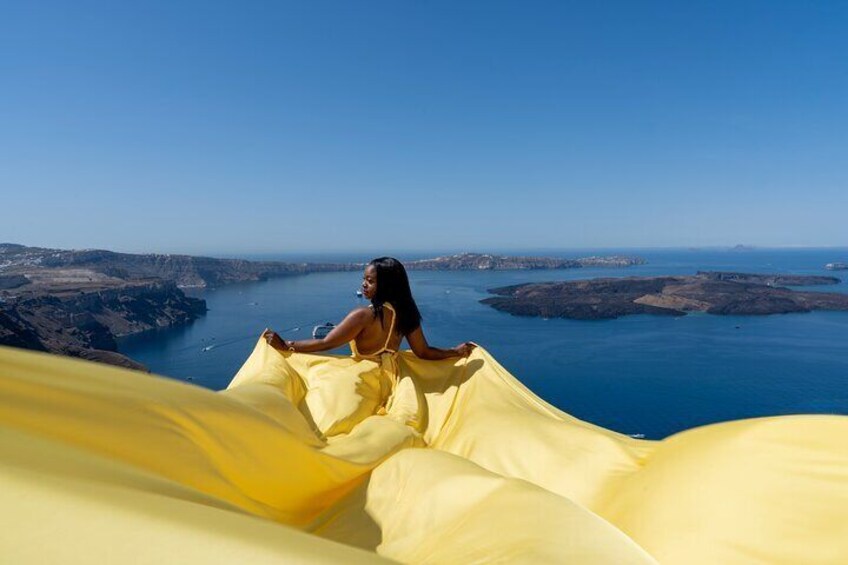 A person sitting on a yellow fabric, overlooking a coastal landscape with cliffs and the sea. 5