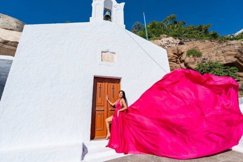 A white building with a wooden door and a bell tower, set against a rocky landscape. 2