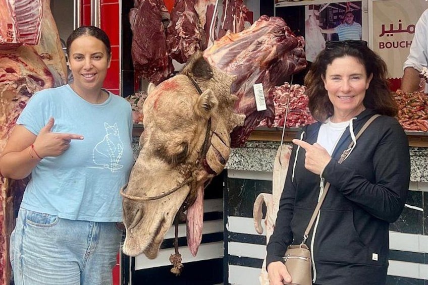 Deux personnes se tiennent devant une boucherie où sont exposées différentes sortes de viandes. 4