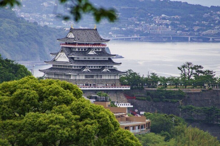 A traditional Japanese castle with multiple tiers, surrounded by lush greenery and overlooking a body of water. 4