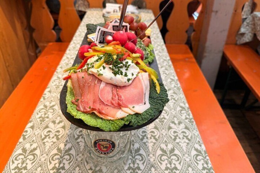 Une longue table sur laquelle est disposé un grand plateau de nourriture comprenant de la viande, du fromage et des légumes. 3