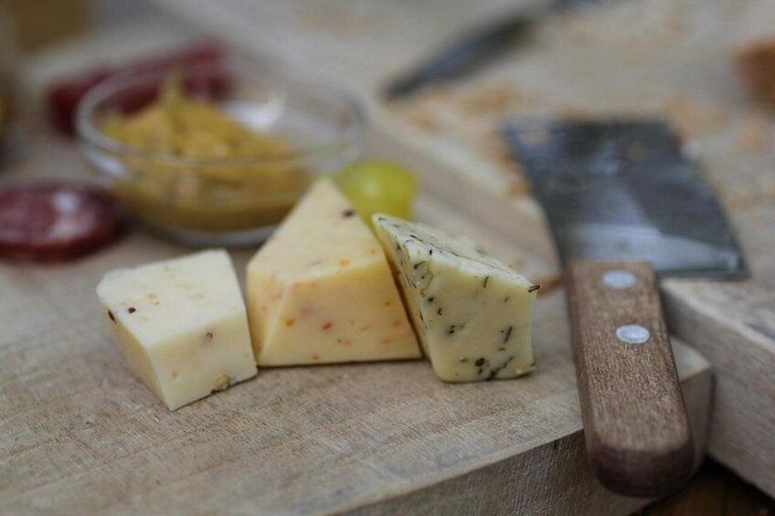 Une planche à découper en bois avec du fromage, un couteau et un bol d’olives. 3
