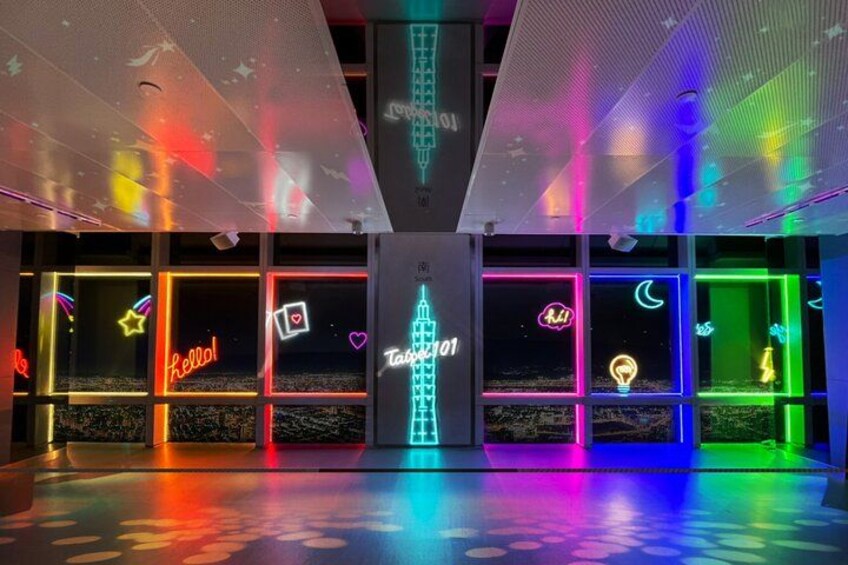 Un espacio interior luminoso con letreros de neón y una estructura central iluminada. 3