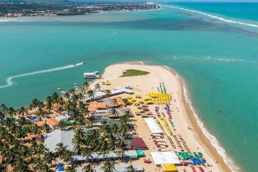 A coastal town with a beach, palm trees, and a clear blue sea. 4