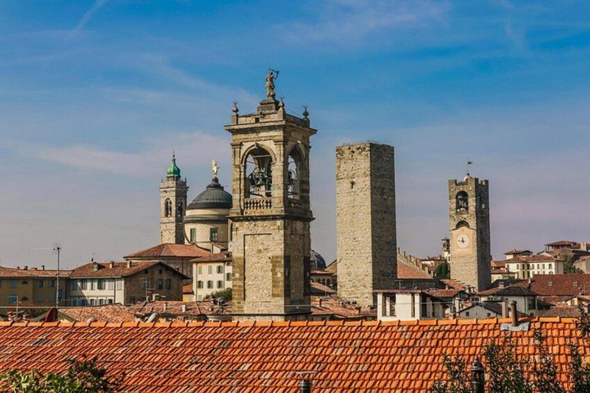 A historic town with a prominent clock tower, a bell tower, and a large stone building. 2