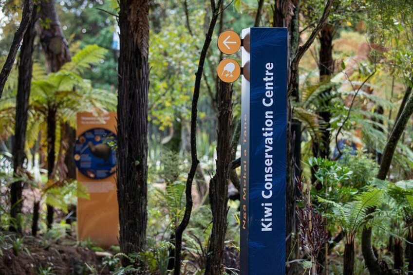 Een bordje voor het Kiwi Conservation Centre, omringd door weelderige begroeiing. 3
