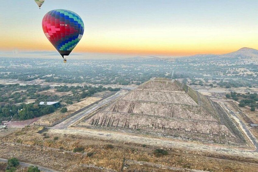 A pyramid with a hot air balloon in the sky. 4