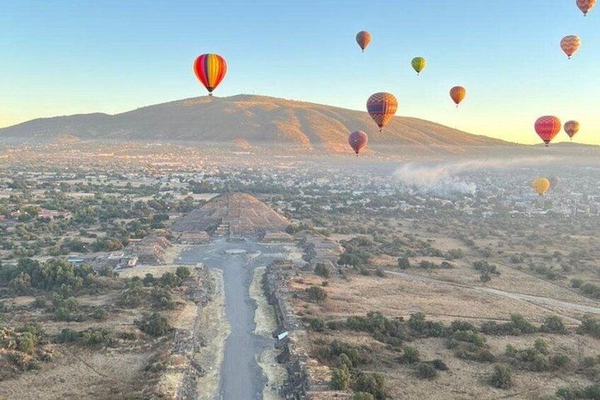 A valley with a river, hot air balloons, and a mountain in the background. 3