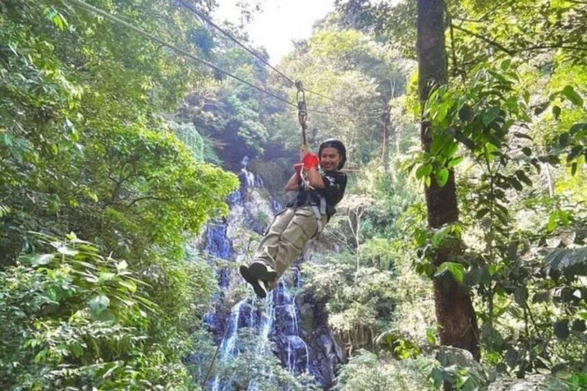 A person suspended in a forested area, swinging on a rope. 1