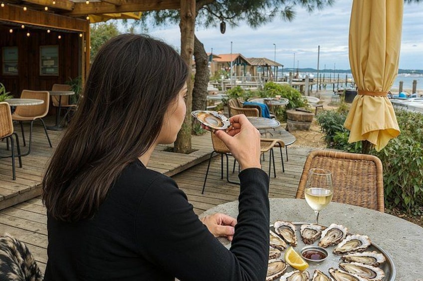 Una persona cenando en un restaurante al aire libre, con una bandeja de mariscos y una copa de vino blanco. 4