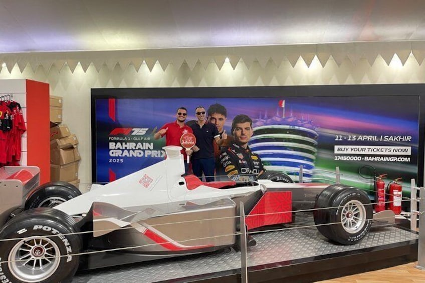 Een Formule 1 auto tentoongesteld met een achtergrond waarop de Grand Prix van Bahrein 2025 wordt geadverteerd. 1