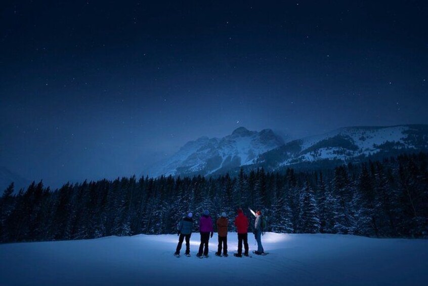 Een besneeuwd berglandschap in de nacht, met een groep mensen op een met sneeuw bedekte helling. 2