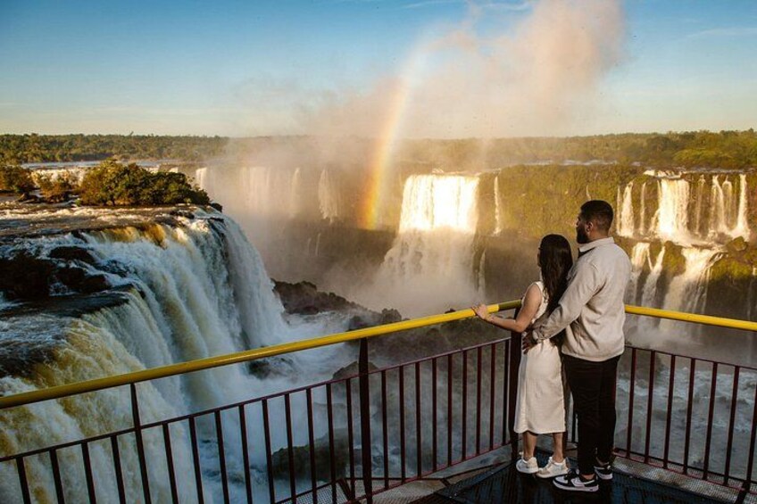Una pareja parada junto a una cascada con un arcoíris. 5