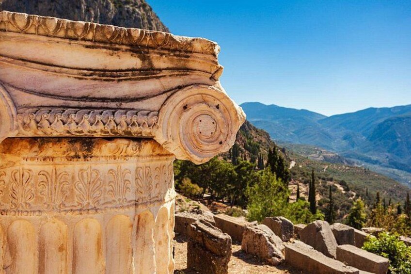 Una colonna classica con decorazioni elaborate, con montagne sullo sfondo. 4