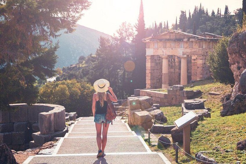 Una persona cammina su un sentiero lastricato con rovine antiche e un tempio sullo sfondo. 5