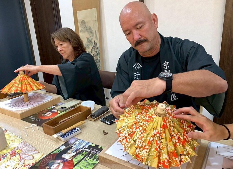 Two people folding traditional Japanese umbrellas. 2