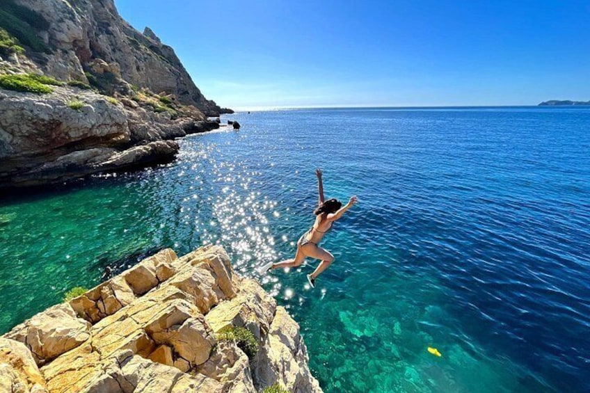 A person jumping into clear blue water from a rocky cliff. 3