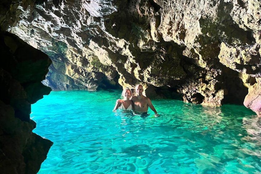 En person i en grotta med klart, turkosfärgat vatten. 1