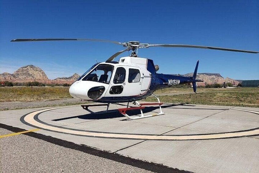 A helicopter parked on a helipad with mountains in the background. 2