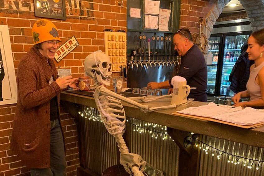 A bar with a skeleton decoration, a beer tap, and a menu. 1
