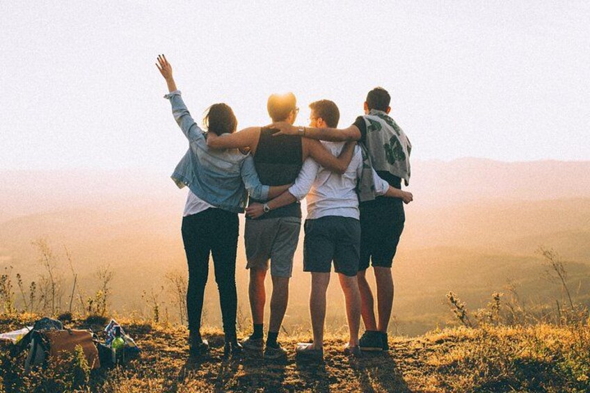 Un groupe de personnes se tient sur une colline, les bras l’un autour de l’autre, et fait face à un paysage montagneux. 4