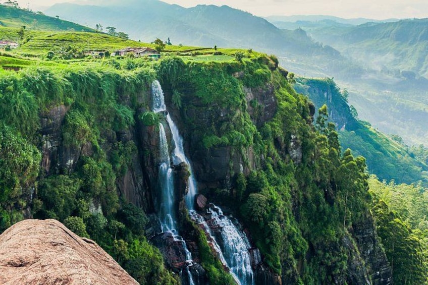 Une cascade se précipite le long d’une falaise verdoyante, entourée d’une forêt dense. 5