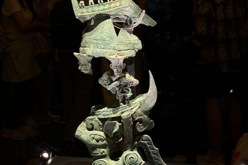 A bronze sculpture with intricate designs and a figure wearing a headdress. 5